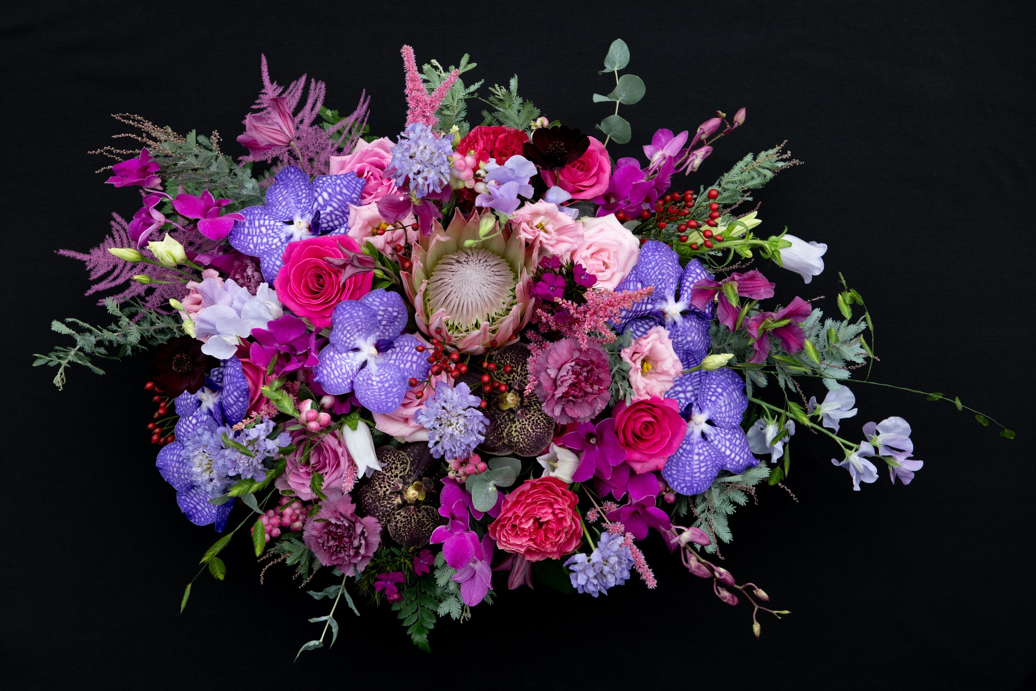 A signature painterly bouquet from Hilary's: deep purple vanda orchids, fuchsia garden roses, and a king protea, hand-tied at the Nantgavenny Lane studio